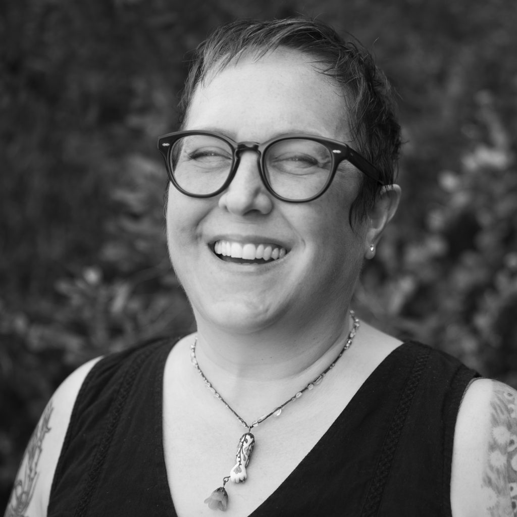 Woman with short hair wearing glasses laughing. 